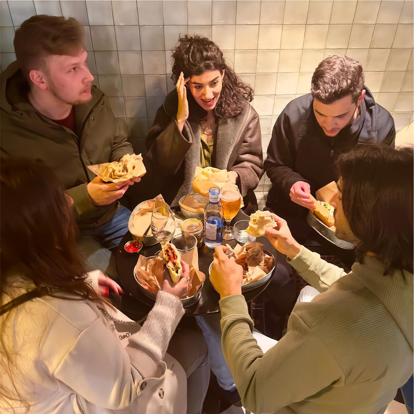 Grupo de amigos comiendo en un una mesa en el interior del restaurante de pitas en Barcelona Dos Manos
